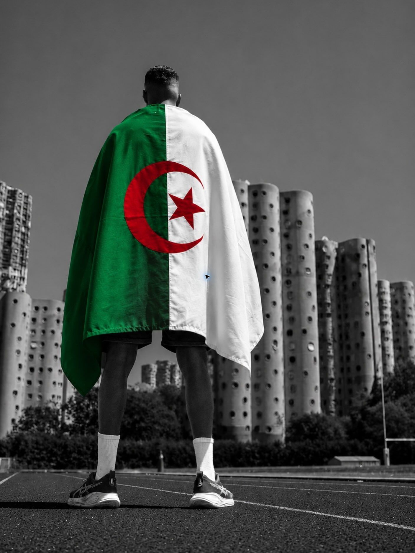 Abdelrahmane Rezzag de dos, enveloppé dans le drapeau algérien devant les tours de Nanterre